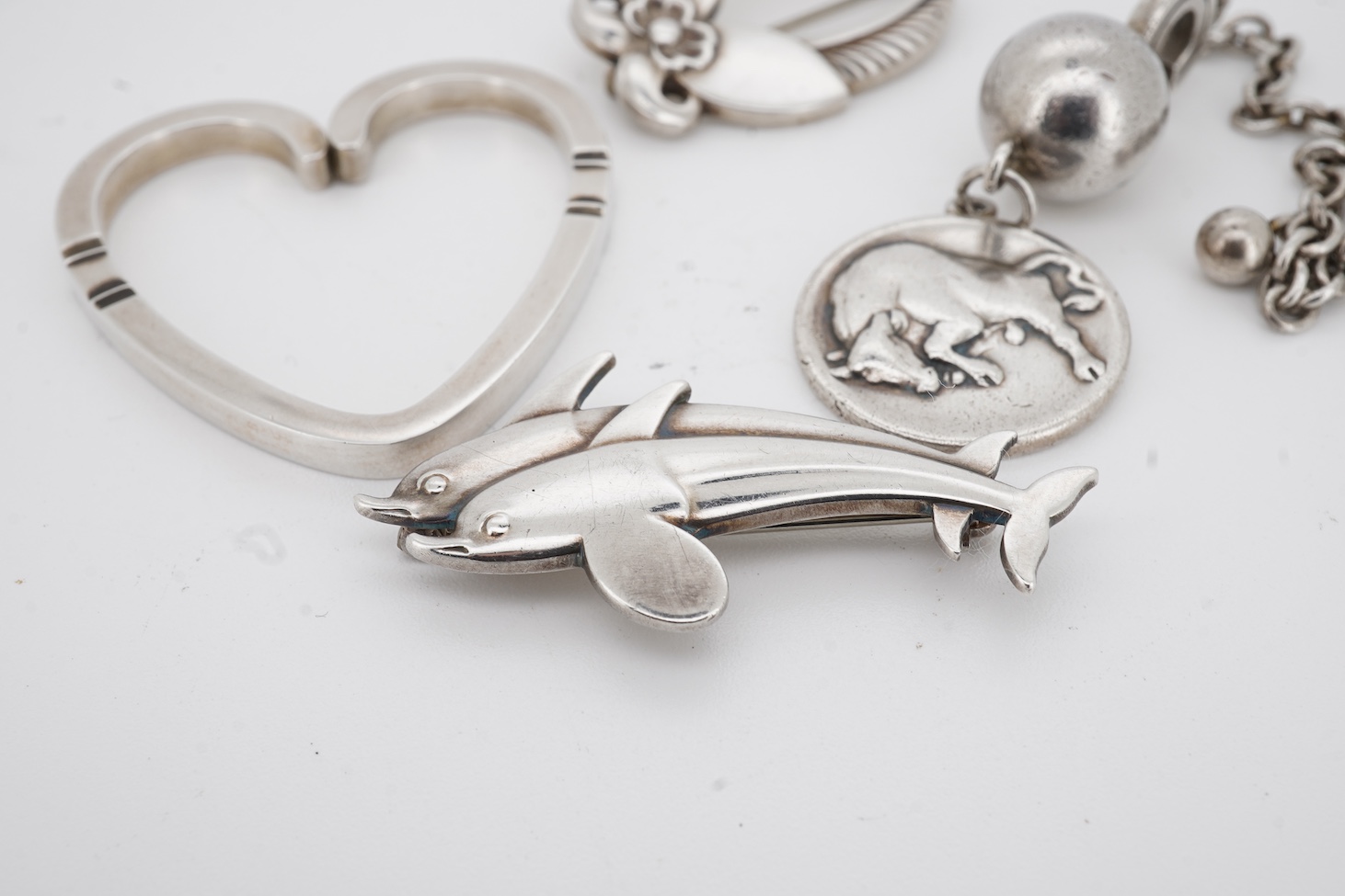 A Danish Georg Jensen sterling twin dolphin brooch, 40mm and a similar flower brooch, design numbers 317 and 227, a 1960's Georg Jensen silver bracelet, design no.46 and a similar 1970's silver heart pendant, design no.4